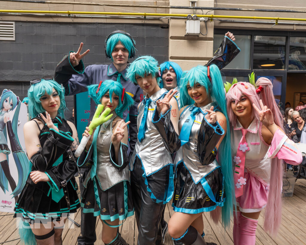 The Organizers of the Hatsune Miku lookalike contest dressed in full Hatsune Miku cosplay as they pose for the camera.