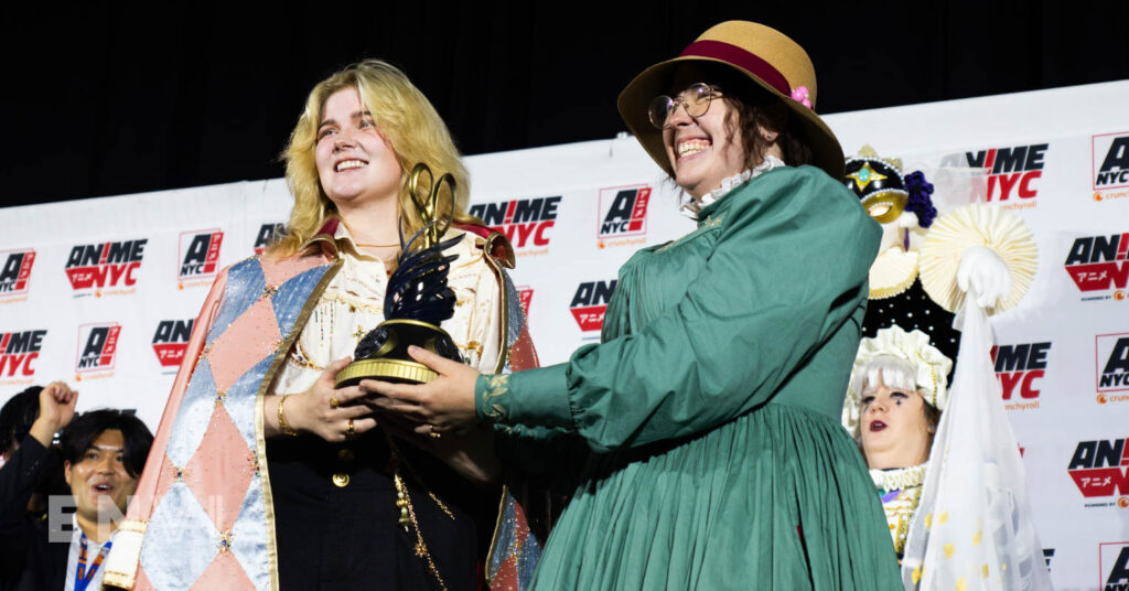 Two cosplayers hold a trophy while dressed as Sophie and Howl from Howl's Moving Castle.