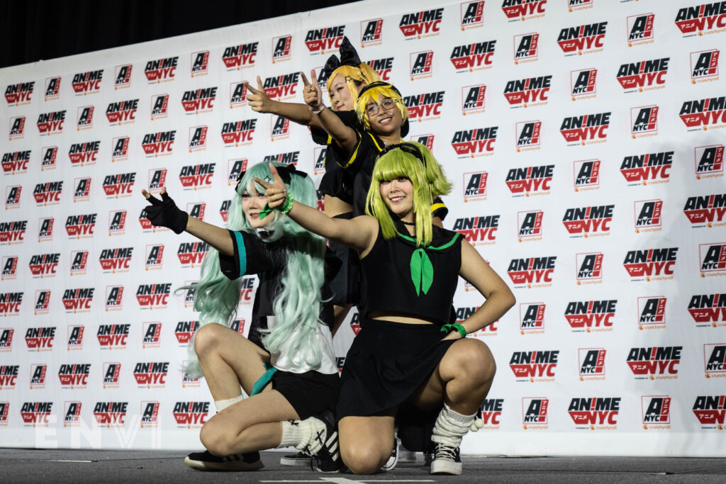 A group of cosplayers dress in black school uniforms while pointing towards the crowd at the Anime NYC 2024 Cosplay Masquerade.