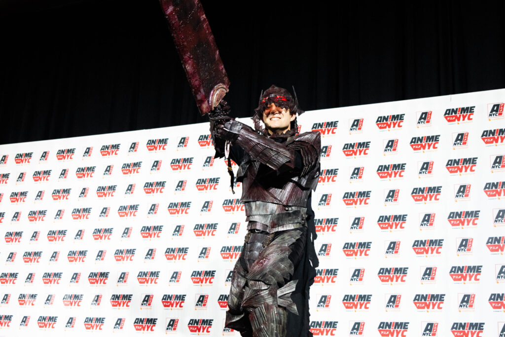 DJ Nutz Cosplay hoists a sword in the air at the Anime NYC 2024 Cosplay Masquerade