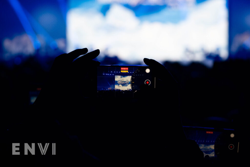 Just minutes ahead of the show, a fan is pictured holding up their iPhone, taking pictures of the tour title card