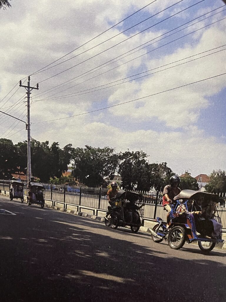 A street in front of the Yogyakarta Palace, with some becak passing by.