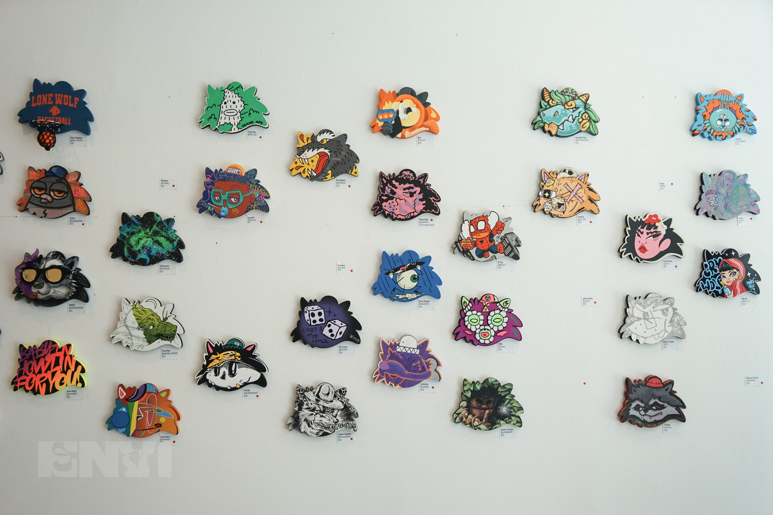 A collection of artworks displayed on a white wall.