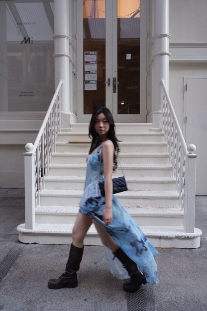 Sujin Gwon in a blue dress, carrying a black handbag.
