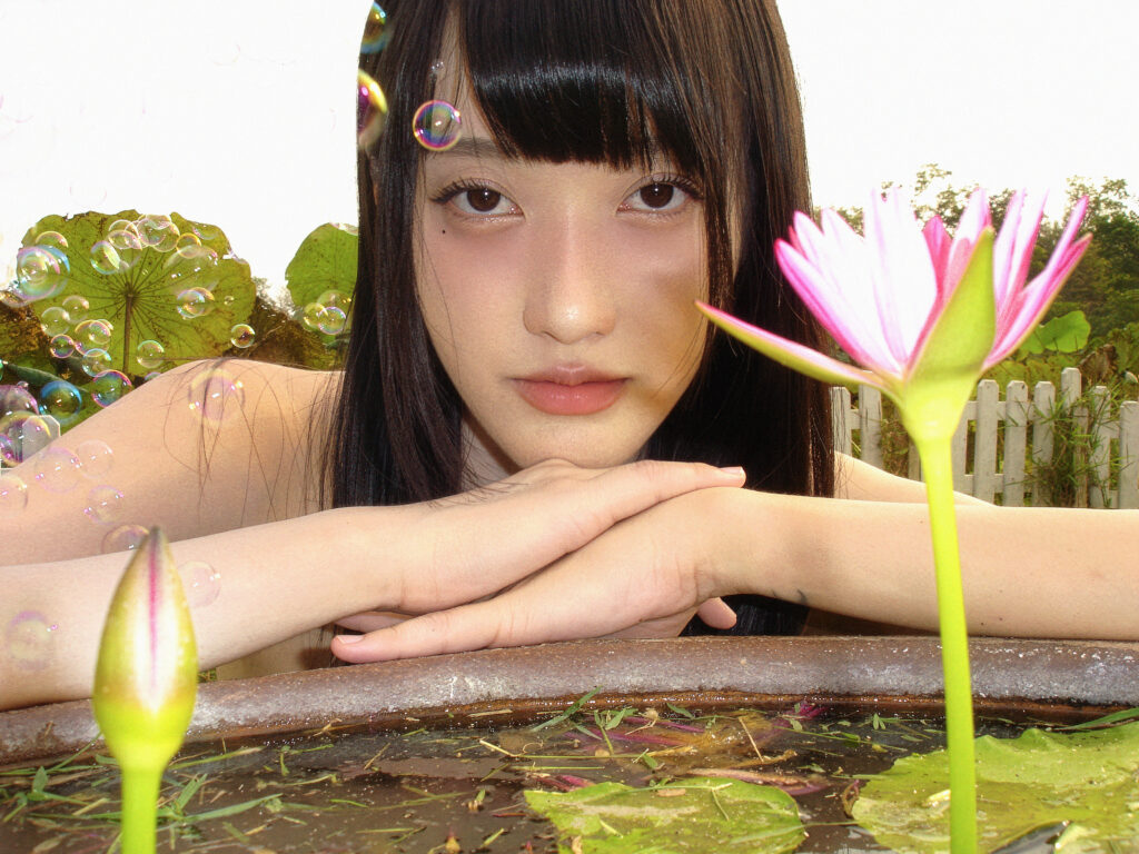 pami Exclusive Interview image; Thai indie artist pami posing next to a pond filled with lotus flowers.