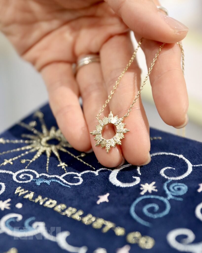 Close up of a hand holding the Sunseeker necklace