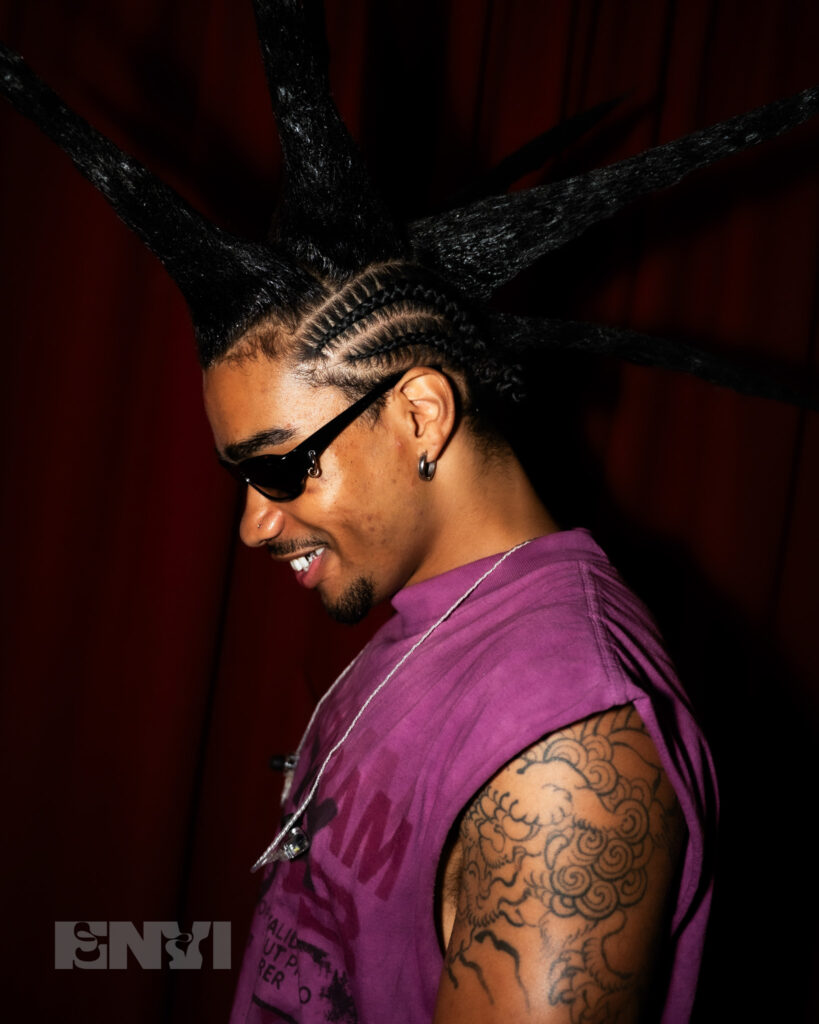 Danny Singh's side profile as he poses for the camera with sunglasses and spikes in his hair.